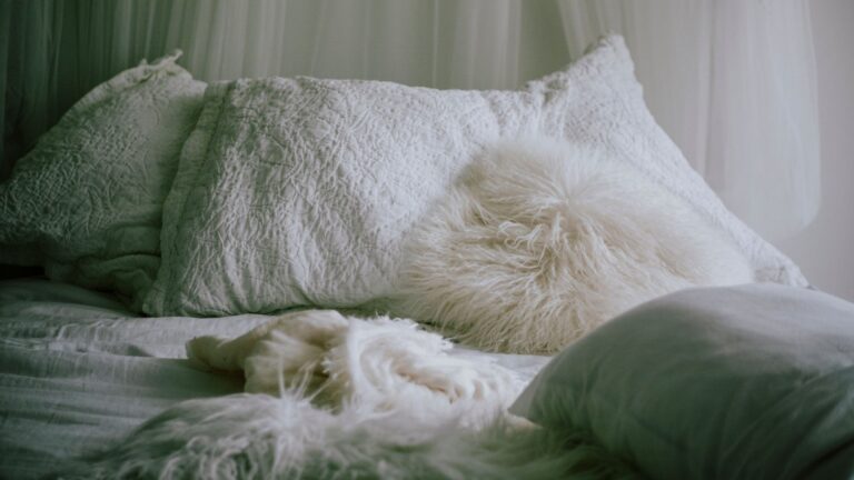 Unmade bed with fluffy white pillows and green bedding