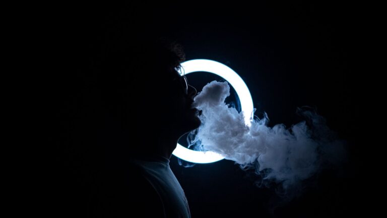 Silhouette of a man exhaling vapor in a dark room