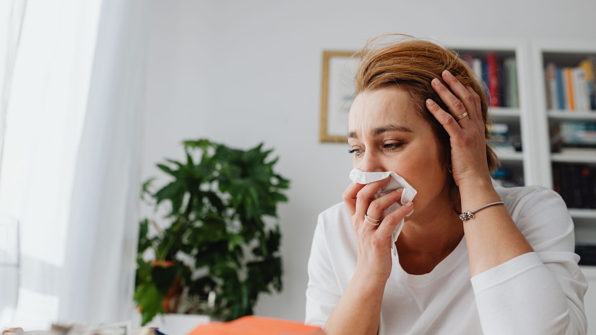 Woman at home blowing her nose into a tissue