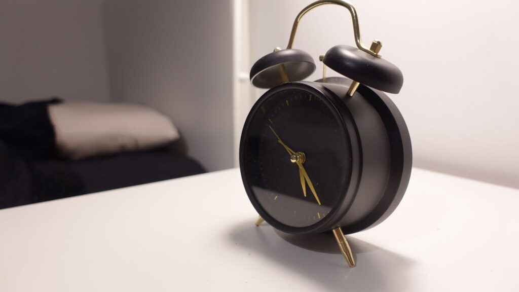 Black twin-bell alarm clock on a white bedside table