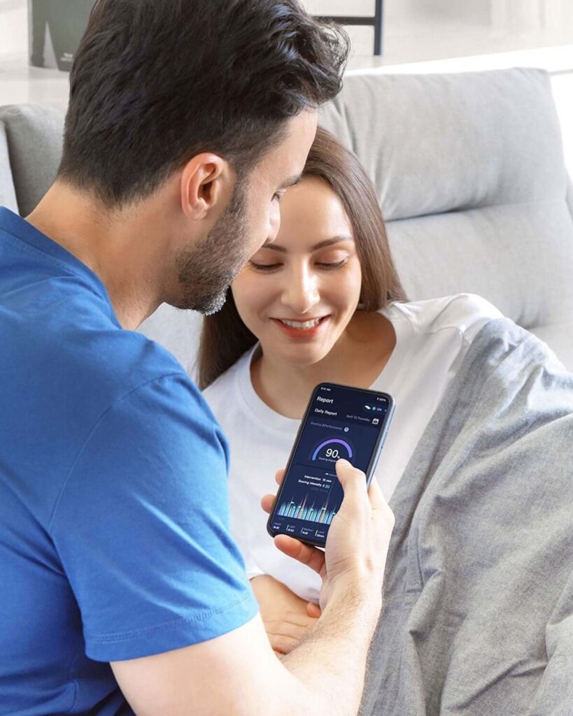 Man and woman reading a Nitetronic app screen on a phone in bed