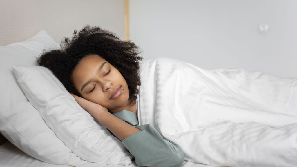 Woman sleeping peacefully on her side in a white bed
