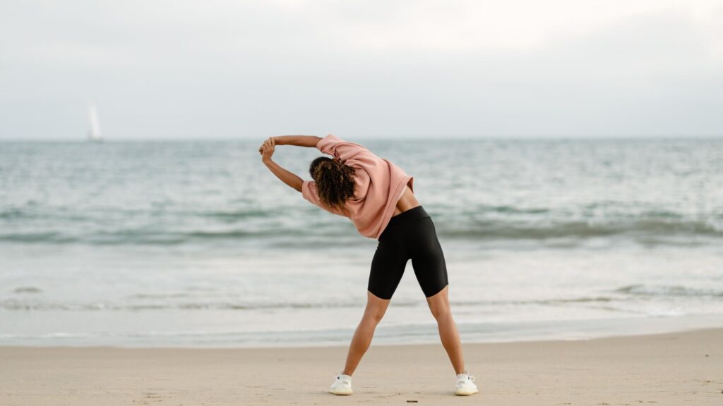 Woman stretching on a quiet beach as part of a daily exercise routine